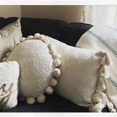 some pillows are sitting on a couch with tassels and pom - poms