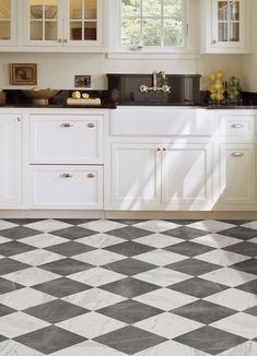 a black and white checkered floor in a kitchen with cabinets, counter tops, and sink