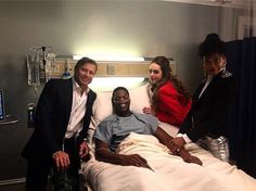 three people standing around a hospital bed with a man in the middle and two women on either side