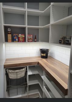 an empty pantry with wooden counter tops and white shelves filled with food, snacks and other items