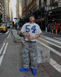 a man standing in the middle of a street with his hands on his hips wearing blue shoes