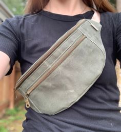 a woman wearing a gray fanny bag with zippers