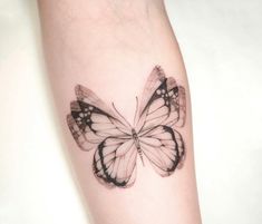 a small butterfly tattoo on the left forearm and right arm is black, white and grey