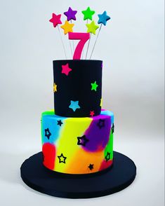 a multi - colored birthday cake with stars on it and the number seven in the middle