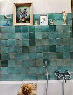 a bathroom with green tiles and pictures on the wall above it, along with a bathtub