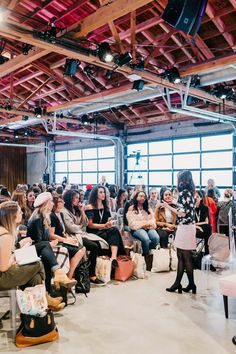 a large group of people sitting in front of a crowd at a fashion show or presentation