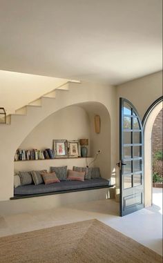 a living room filled with furniture and a book shelf on top of a stair case