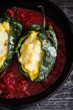 two stuffed green peppers in a red sauce