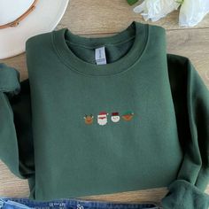 a green sweatshirt with three santas embroidered on it