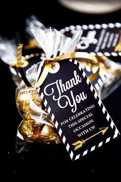 a thank you bag filled with chocolates on top of a black tablecloth and gold ribbon