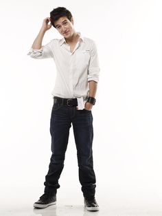 a young man standing with his hands on his head and looking at the camera while wearing jeans