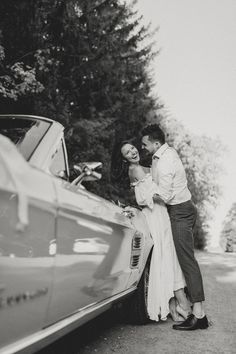 a man and woman standing next to a car