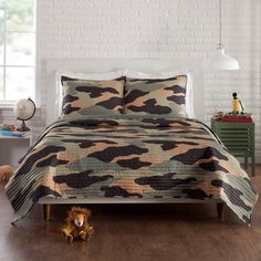 a bed in a room with a camo bedspread and pillows