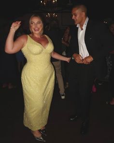 a woman in a yellow dress and a man in a black suit dancing at a party