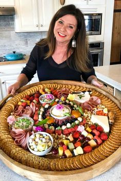 a woman standing in front of a platter full of food