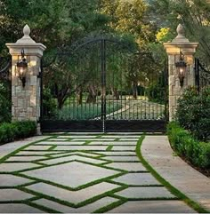 an entrance to a home with stone walkway and iron gates, surrounded by greenery