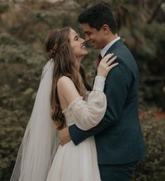 a bride and groom embracing each other in front of trees