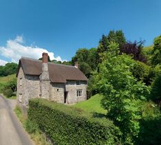 an old stone house with a thatched roof in the middle of a country road