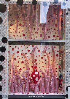 a window display with polka dot curtains and red vases in the front, surrounded by black and white dots