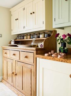 an old fashioned kitchen with wooden cabinets and white cupboards on the wall, filled with pots and pans