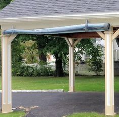 a white and blue covered gazebo sitting on top of a lush green park next to a house