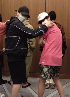 two people are hugging each other in front of a group of people wearing face masks