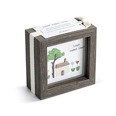 a small wooden box with a house and tree on the inside, in front of a white background