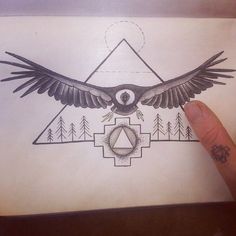 a hand holding up a piece of paper with an eagle and triangle tattoo on it