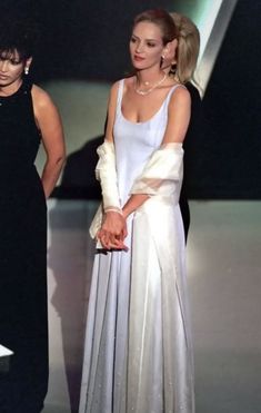 two women standing next to each other on a stage with one woman wearing a white dress