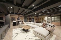 a large living room with white couches and wooden tables in the middle of it