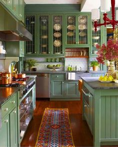 a kitchen filled with lots of green cabinets and counter top space next to a stove top oven