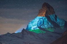 the mountain is illuminated with colorful lights on it's side and stars in the sky above