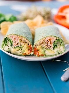 there is a plate with two wraps on it and some vegetables in the background,