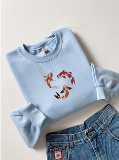 Dive into a sea of style with our Embroidered Koi Fish Sweatshirt, a Japanese-inspired masterpiece that combines comfort and aquatic elegance. This koi fish sweatshirt isn't just an article of clothing; it's a wearable work of art. Crafted with precision and featuring intricate embroidery, the Japanese koi fish takes center stage, creating a unique and visually stunning design. This sweatshirt seamlessly blends Japanese aesthetics with marine elements, making it a versatile addition to your wardrobe. Whether you're a fan of ocean life, Japanese culture, or simply appreciate unique fashion, this koi fish shirt is a must-have. Swim against the current of ordinary style and make a splash with our Koi Fish Sweatshirt - the perfect catch for those who love marine motifs and Japanese flair. A st Koi Fish Shirt, Marine Motifs, Shark Sweatshirt, Japanese Koi Fish, Fish Shirt, Japanese Koi, Shark Shirt, Embroidered Crewneck, Embroidered Clothes