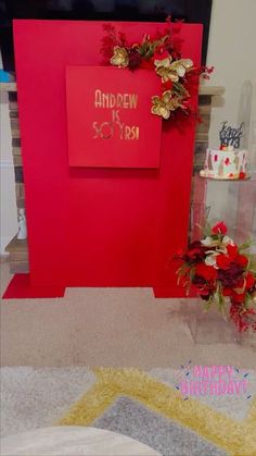 there is a red wall with flowers on it and a sign that says happy birthday