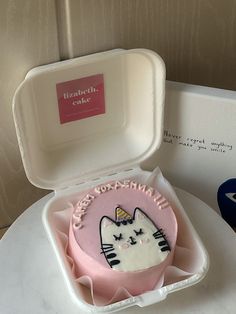 a cake in a box with a cat design on the inside and pink frosting