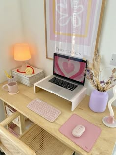 a laptop computer sitting on top of a wooden desk next to a pink mouse pad