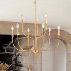 a gold chandelier hanging from the ceiling in a living room with fireplace and brick wall