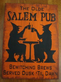 an old salem pub sign with witches sitting at a table and one holding a beer