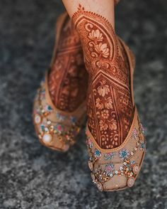 the legs and feet of a woman with henna tattoos on her body, wearing high heeled shoes