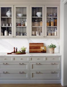 a kitchen with white cabinets and wooden cutting board on the counter top in front of it