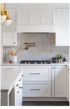 a kitchen with white cabinets and marble counter tops, gold pendant lights over the stove