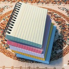 four notebooks stacked on top of each other in front of a floral area rug