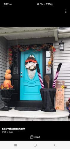 a blue front door decorated for halloween with pumpkins and witch's legs on the porch