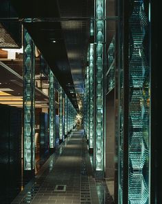 an empty hallway between two buildings with glass walls on both sides and tiled flooring