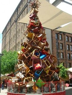 a christmas tree made out of baskets and other items in front of a large building