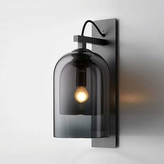 a wall light that is on the side of a white wall with a black glass shade