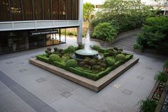 a fountain in the middle of a courtyard surrounded by greenery