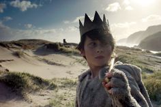 a young boy wearing a crown on top of his head holding a piece of bread