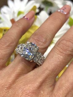 a woman's hand with a diamond ring on top of her finger and two diamonds in the middle